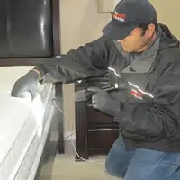 Bed bug inspection technician checking a mattress and bed frame for signs of infestation in Nashville, TN