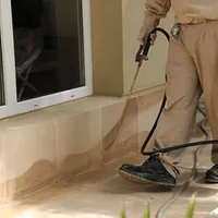 General pest control technician spraying exterior perimeter around a home in Nashville, TN