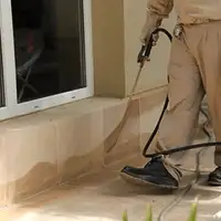 General pest control technician spraying exterior perimeter around a home in Nashville, TN